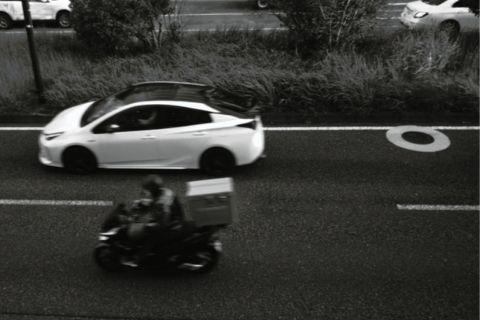 道路を走行する白い車と黒いバイク