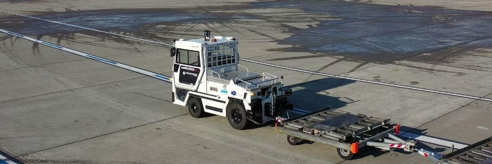 NAVYA autonomous driving towing tractor that transports containers at the airport