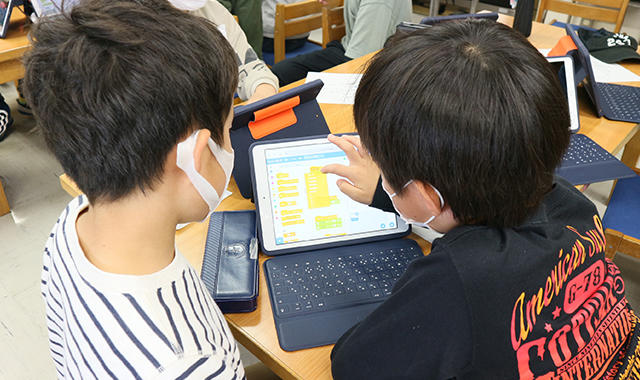 近隣地域の篠原小学校プログラミング部の生徒の皆さんに対して、ロボットを用いたプログラミング教室を実施している様子（写真2）
